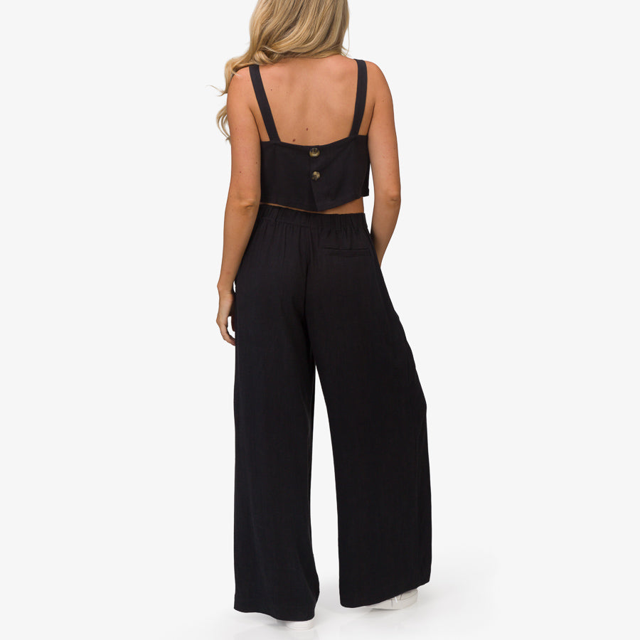 Back view of woman wearing black Tori Linen Pant with elastic waistband, styled for beach and active lifestyles.