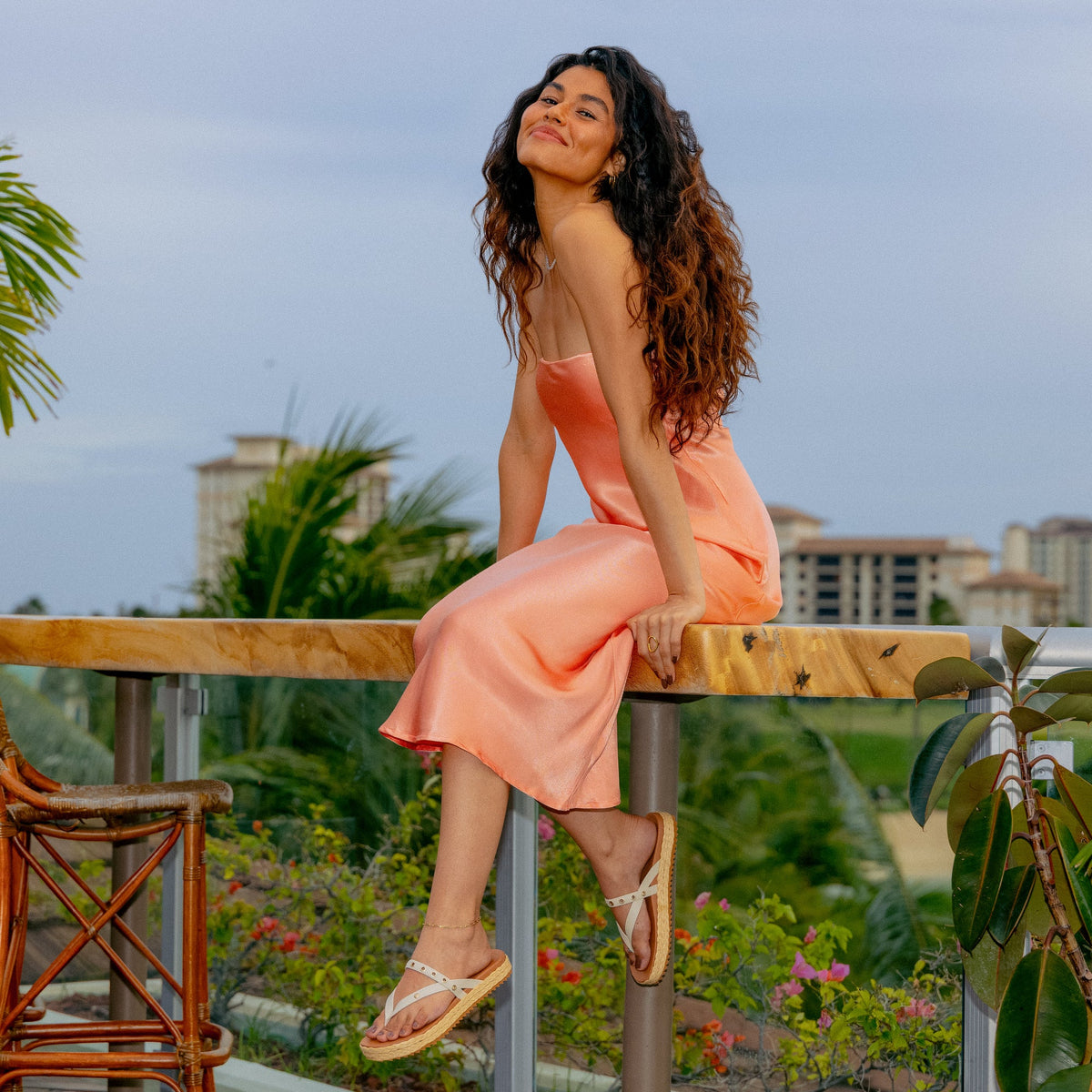 Woman wearing Vista Carmen sandals facing right, seated outdoors with beach-inspired comfort and arch support design.